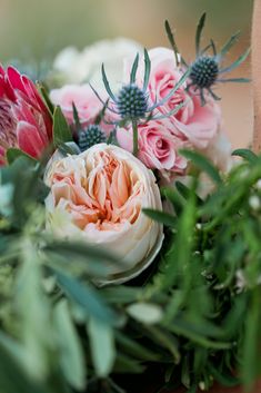 a bouquet of pink and white flowers sitting on top of green leaves