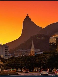 the sun is setting over a city with mountains in the background and cars driving on the road