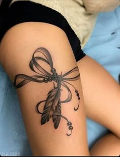 a woman's thigh with a tattoo design on her leg and an arrow in the shape of a bow