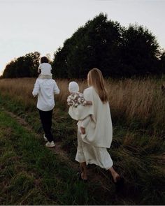 two people walking down a path in the grass with one person wearing a white coat