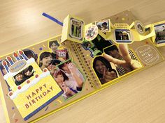 a yellow birthday card with pictures and words on it, sitting on a wooden table