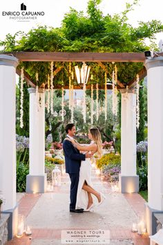 a bride and groom are dancing under an arbor with candles in the background at their wedding