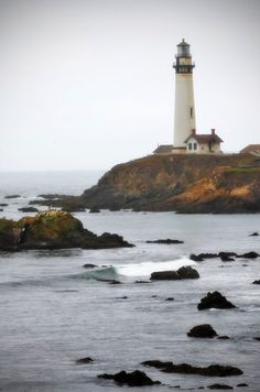 a light house sitting on top of a small island next to the ocean with waves coming in