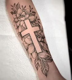 a cross with flowers and leaves on the arm