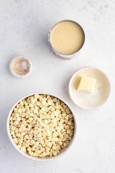 two bowls filled with food next to some butter and spoons on a white surface