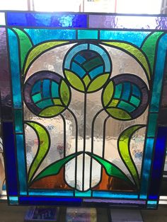 a stained glass window with flowers and leaves in the center, on top of a table