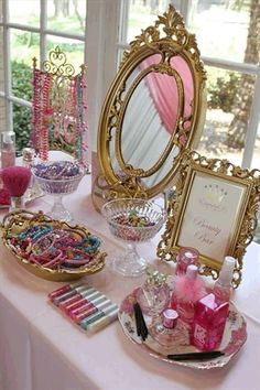 a table topped with lots of pink and gold items next to a mirror on top of a window sill