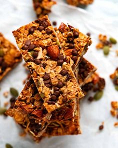 granola bars stacked on top of each other with nuts and seeds scattered around them