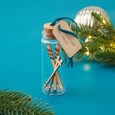 two wooden skis in a glass jar on a blue surface with christmas decorations around it