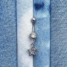 a pair of silver stars dangling from the side of a blue jean fabric with a white background