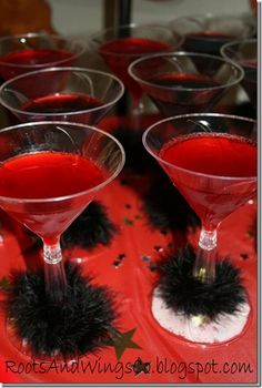 red liquid in martini glasses with black pom - poms