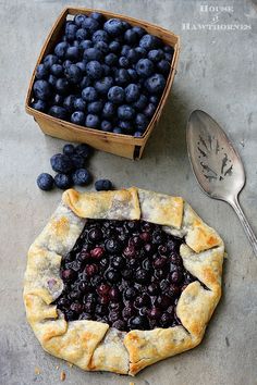 a blueberry crostaa pie sitting on top of a table next to a box of blueberries