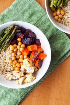 two bowls filled with food on top of a wooden table next to a green towel