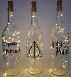 three harry potter bottles with fairy lights on the bottom and one in the middle, both empty