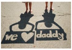 two people are standing on the sidewalk with their shadow in front of them that says we love daddy