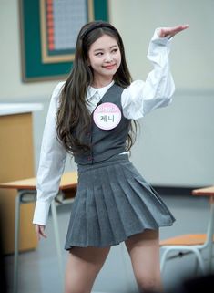 a girl in a school uniform is posing for the camera with her hand up and smiling