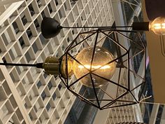 two light bulbs hanging from the ceiling in an office building with high rise buildings behind them