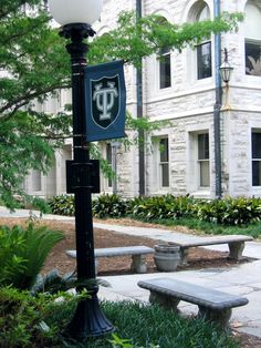 a light pole with a sign on it in front of a building and bench outside