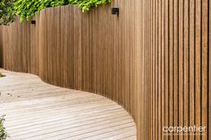 a wooden fence with green plants growing on the top and bottom part, along side it