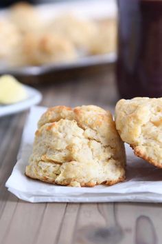 two biscuits sitting on top of a napkin next to a cup of coffee