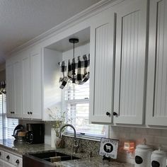 a kitchen with white cabinets and granite counter tops, black and white checkered valance