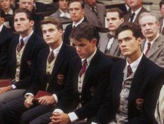 a group of men sitting next to each other in front of an audience at a sporting event