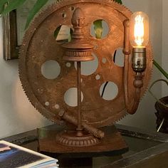 an old movie projector lamp sitting on top of a table next to a plant