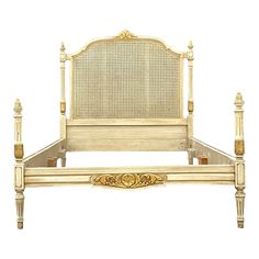 a white bed with gold trimmings and headboard on top of it's frame