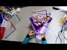 a person is holding up a purple box with candy in it and some other items on the table