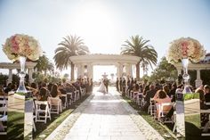 a wedding ceremony in front of an outdoor gazebo with flowers and greenery on either side