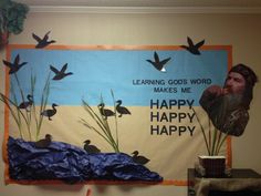 a bulletin board is decorated with birds and grass in front of a man's face