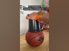 a man is holding a basketball on top of a trash can with an orange band around his arm