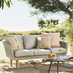 a couch sitting on top of a stone floor next to a table with two apples