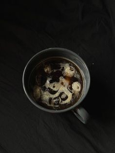 a pan filled with food sitting on top of a black cloth covered table next to a knife