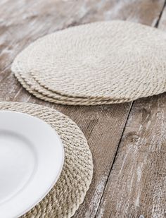 two white plates sitting on top of a wooden table next to each other and one is empty