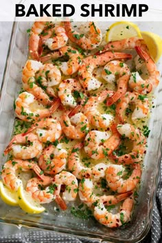 a glass casserole dish filled with shrimp and garnished with lemon wedges