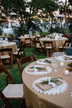 an outdoor wedding reception set up with table linens, place settings and candle lights