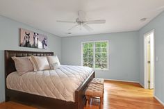 a bedroom with blue walls and hardwood floors, including a bed that has white pillows on it