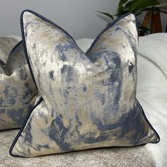 two blue and gold pillows on a bed