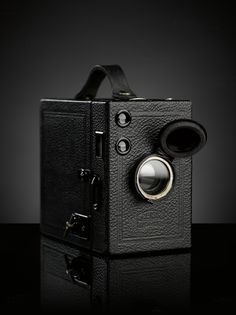 an old fashioned camera on a black surface