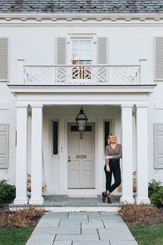 a woman standing in front of a white house