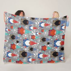 two women holding up a blanket with snowflakes on it