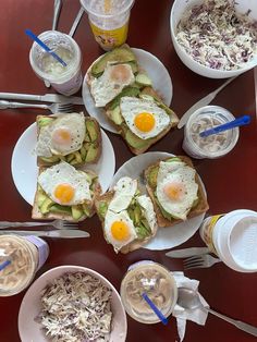 several plates with food on them sitting on a table next to cups of drinks and spoons