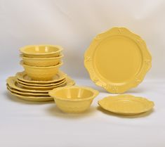 a stack of yellow plates and bowls sitting next to each other on a white surface