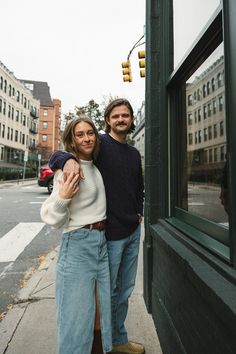 a man and woman standing next to each other in front of a building on a city street