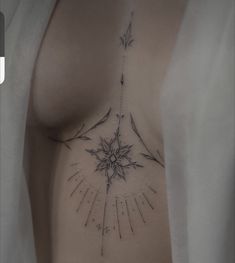 a woman's chest with an arrow and sunburst tattoo on her left side