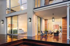 a house with wooden decking and glass doors leading to the outside patio area at night