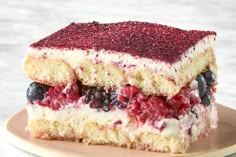 a piece of cake on a plate with berries and blueberries in the top layer