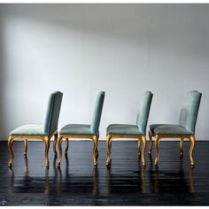 four chairs are lined up in a row on a black floor with white walls behind them