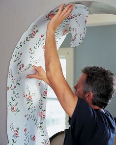 a man is working on a curtain in the living room with his hands hanging from it